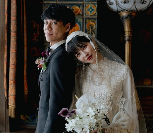 新郎の背中に頭を預けて微笑む、ベールを纏った新婦のポートレート